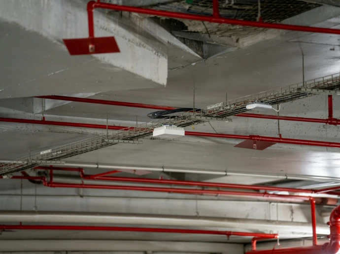 Concrete ceiling with red pipes and cable trays.